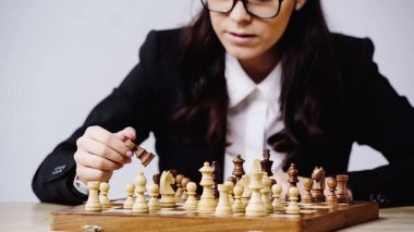 partial view of businesswoman playing chess isolated on grey