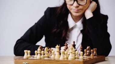 cropped view of businesswoman in glasses playing chess isolated on grey