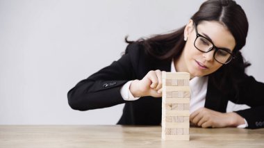 young businesswoman playing blocks wood tower game isolated on grey