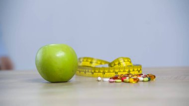 measuring tape, green apple and vitamins isolated on grey