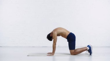 Beyaz tuğla duvarın yanında spor yapan sporcunun yan görüntüsü 