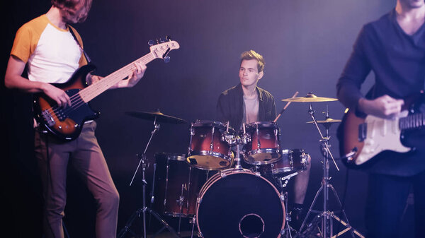 blurred guitarists and drummer performing on stage