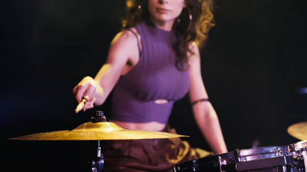 cropped view of blurred drummer playing on drums during performance on stage 
