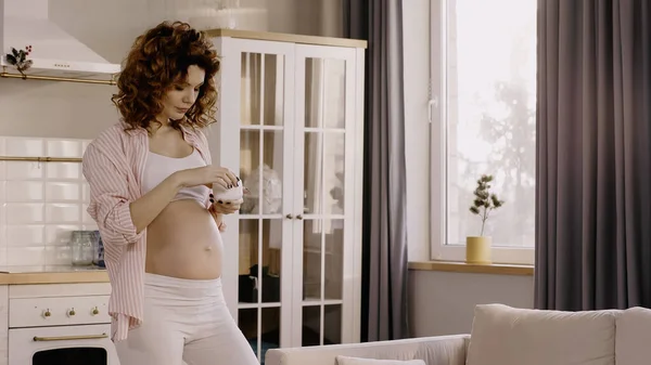 怀孕妇女在家里拿着装有化妆品的容器 — 图库照片