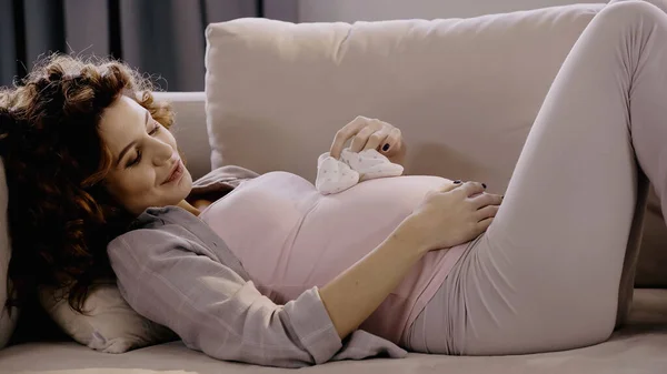 幸せな妊娠中女性保持赤ちゃんおっぱい上のカウチにホーム — ストック写真