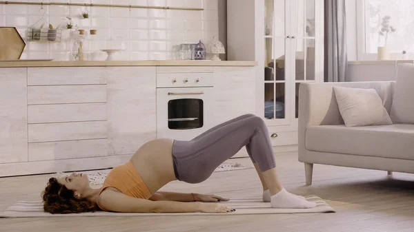 孕妇在家健身垫上运动的侧视图 — 图库照片