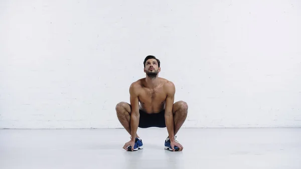 Full Length Sportsman Squatting Sit Position White Brick Wall — Stock Photo, Image