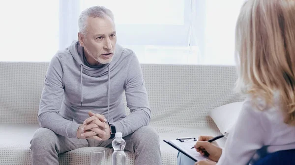 Upset Middle Aged Man Sportswear Sitting Couch Talking Blurred Psychotherapist — Foto Stock