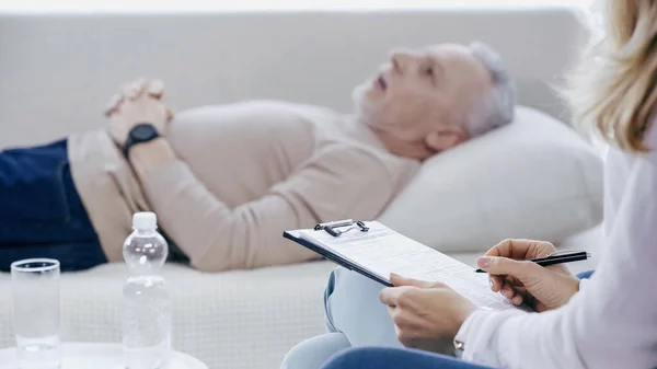 Psychologist Holding Clipboard Middle Aged Man Lying Sofa Therapy — Stockfoto