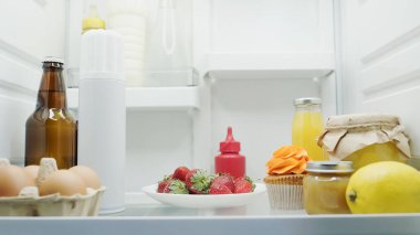 Bira, yumurta, taze çilek, limon, kek, portakal suyu, bal ve soslar buzdolabında.
