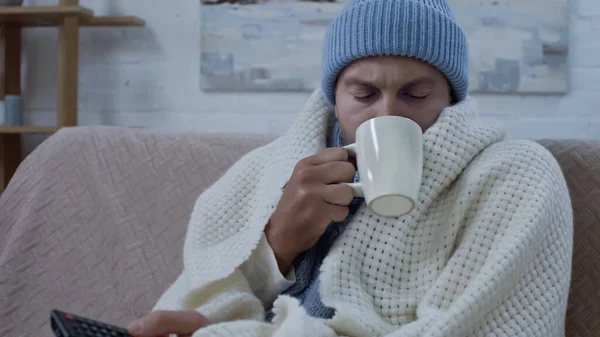 Diseased Man Remote Controller Drinking Tea While Sitting Couch Warm — Fotografie, imagine de stoc