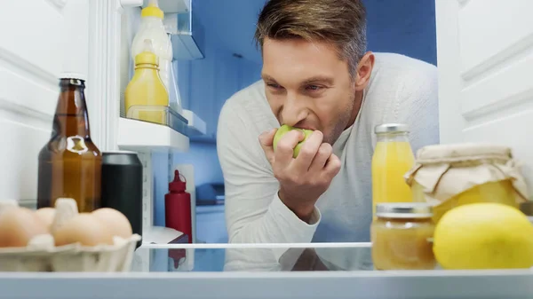 Man Eating Ripe Apple Fridge Eggs Beverages Containers Jars Food — Fotografia de Stock