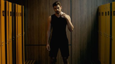 confident sportsman standing with towel in locker room