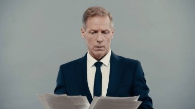 Businessman looking at papers isolated on grey 