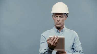 Engineer in hardhat using digital tablet isolated on grey 