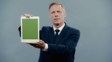 Blurred businessman holding digital tablet with chroma key isolated on grey 