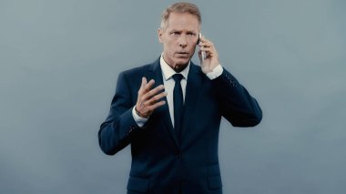 Mature manager talking on cellphone isolated on grey 
