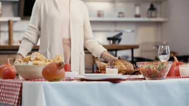 cropped view of blurred woman standing near festive dinner served for thanksgiving