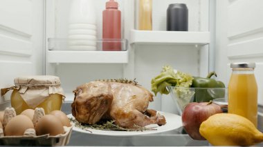 roasted turkey prepared for thanksgiving dinner near fresh vegetables, fruits and containers with food in fridge