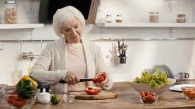 senior woman peeling bell pepper while preparing thanksgiving dinner