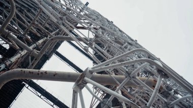 bottom view of old radio tower in chernobyl zone against grey sky