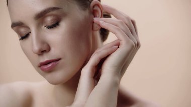 young woman with clean face and closed eyes isolated on beige 