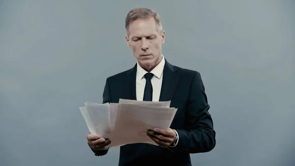 Mature manager holding documents isolated on grey