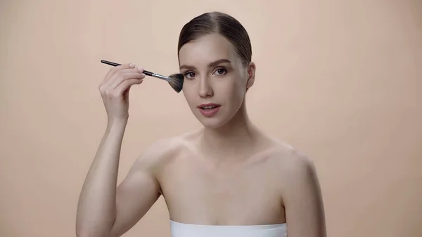 Young Woman Bare Shoulders Applying Face Powder While Holding Cosmetic — стоковое фото