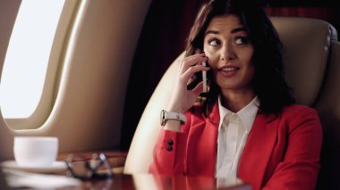 Smiling businesswoman talking on cellphone in private plane 