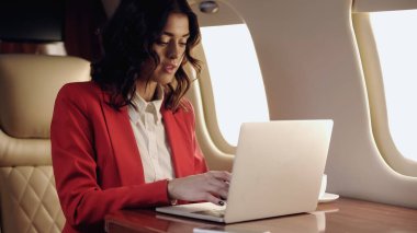 Young businesswoman using laptop in private jet 