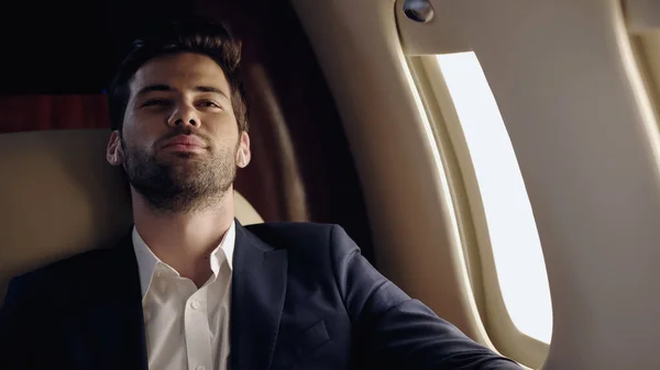 Pleased businessman in earphones sitting in private jet