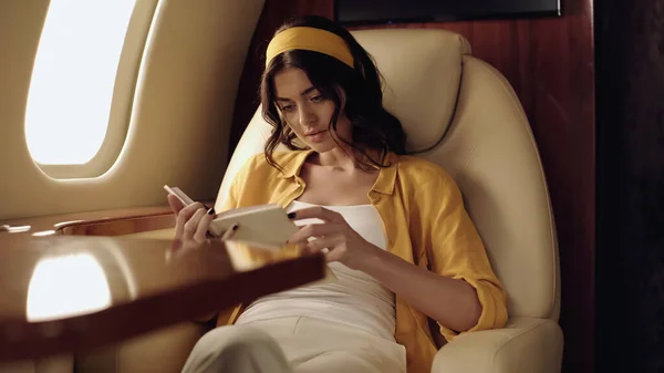 Young woman reading book in private plane