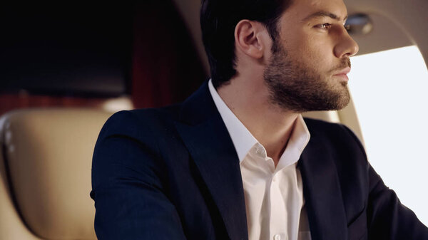 Bearded businessman in suit in private jet 