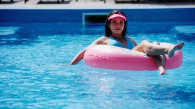 Yazın yüzme havuzunda yüzen mutlu genç bir kadın.