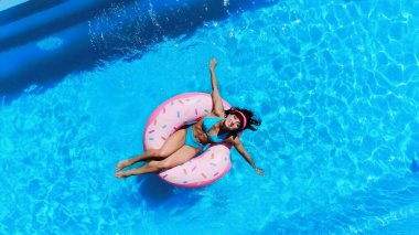top view of cheerful woman swimming on swim ring in pool 