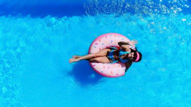 top view of cheerful woman swimming on swim ring and waving hand in pool