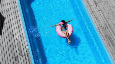 top view of barefoot woman swimming on swim ring in pool
