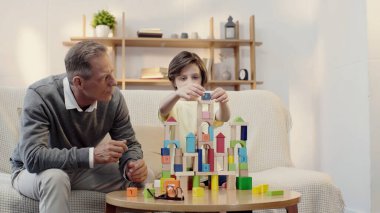 orta yaşlı büyükbaba küçük çocukla inşaat blokları oynuyor.
