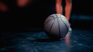 partial view of blurred sportsman standing near basketball on dark background