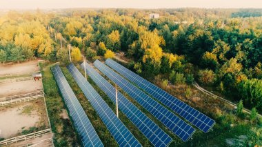 Aerial view of solar panels system on field near forest 