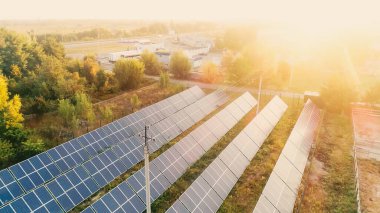 Aerial view of solar panels and power lines at sunset 