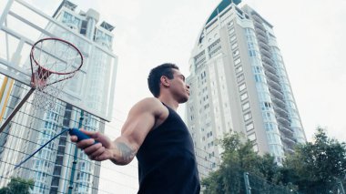Çift ırklı sporcu eğitiminin düşük açılı görüntüsü ve atlama halatı açık havada.