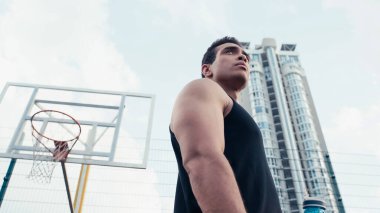 Düşük açılı sporcu melez adam basketbol sahasının yakınından dışarı bakıyor.