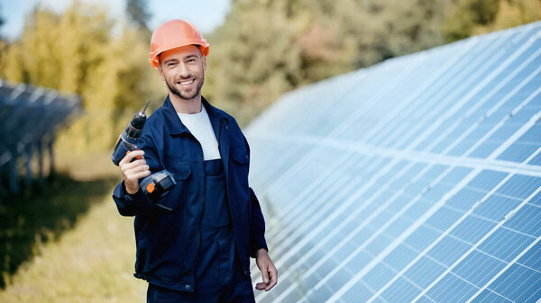 happy engineer in hardhat showing electric drill