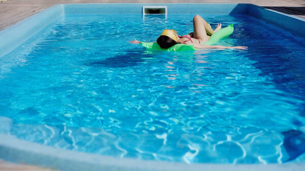 young woman swimming on pool float in blue water