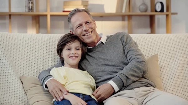 cheerful middle aged grandfather smiling with happy grandson