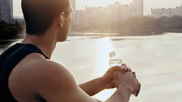 Joven Deportista Racial Con Botella Agua Mirando Amanecer Sobre Río — Foto de Stock