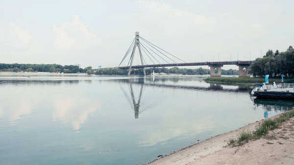 bridge over wide river under cloudy sky