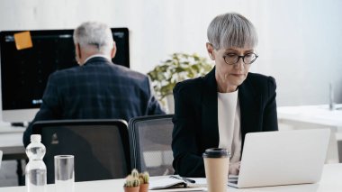 Not defterinin yanında dizüstü bilgisayar ve içki kullanan olgun bir iş kadını. 