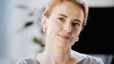 İş kadını bulanık ofiste kameraya bakıyor. 